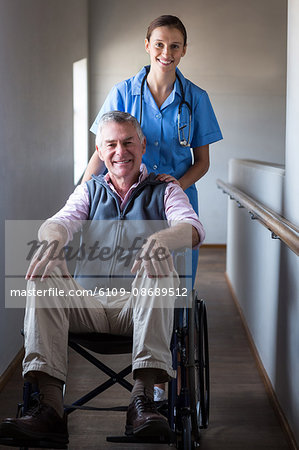 Portrait of smiling senior man and female doctor in corridor at hospital