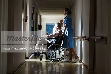 Patient in a wheelchair pushing by a nurse in hospital corridor