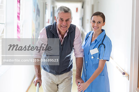 Nurse helping senior patient with walking frame in hospital corridor