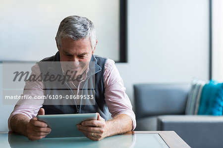 Senior man in medical clinic using digital tablet