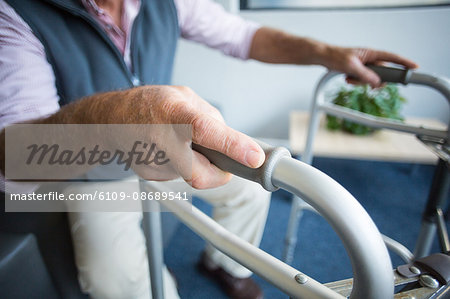 Senior man in hospital trying to stand with the help of walking frame