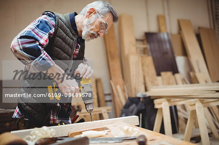 Carpenter drilling a plank of wood in carpentry