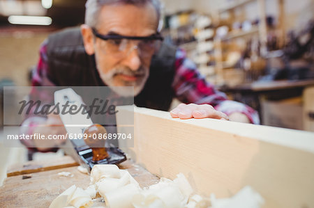 Carpenter using a sander to make smoother a wood plank in his workshop Carpenter using a sander to make smoother a wood plank in his workshop