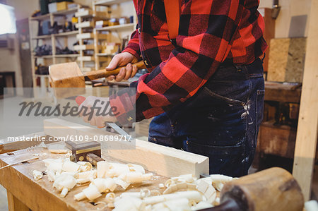 Carpenter working on wooden plank in his workshop