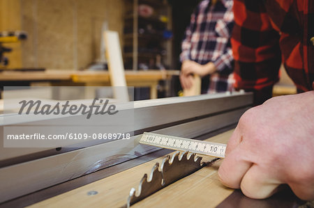 Carpenter measuring wood plank in workshop Carpenter measuring wood plank in workshop