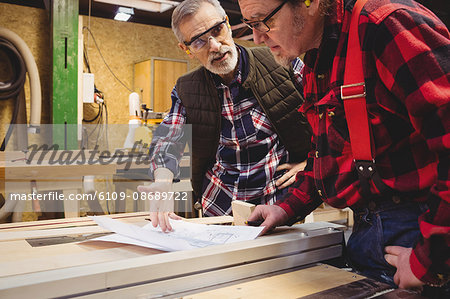 Duo of carpenter working on a wood plank in their workshop Duo of carpenter working on a wood plank in their workshop