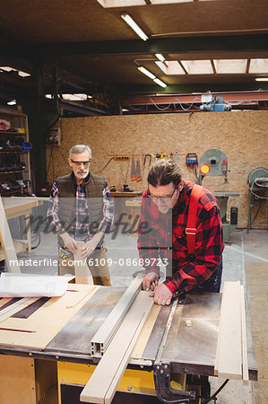 Duo of carpenter working on a wood plank in their workshop Duo of carpenter working on a wood plank in their workshop