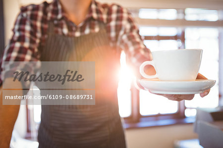 Waiter holding cup of coffee in a cafe