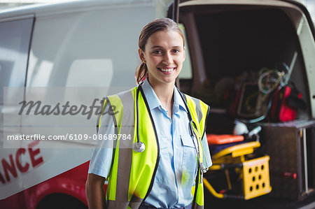 Portrait of smiling ambulance woman in front of ambulance car