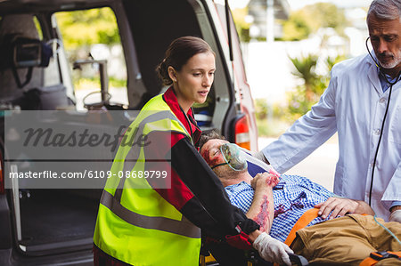 Ambulance crew and doctor taking care of an injured person in front of the ambulance vehicule