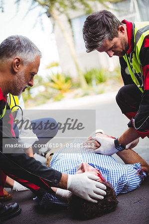 Ambulance man taking care of injured man lying on the floor