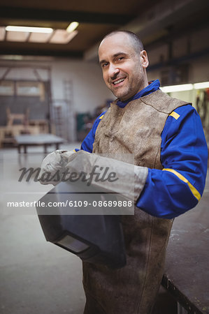 Side view of welder smiling and posing in his workshop