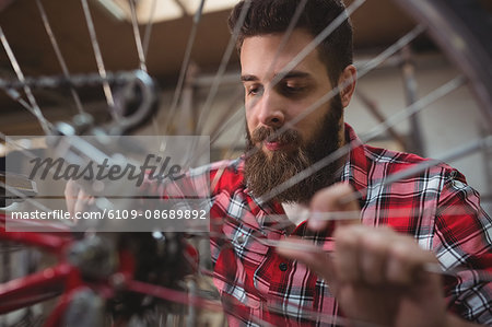 Close up of mechanic repairing a bicycle wheel in his workshop