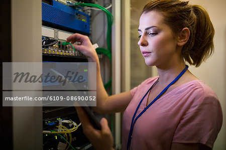 Technician using digital tablet in server room