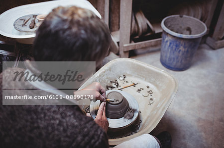 Rear view of craftsman preparing ceramic container in workshop