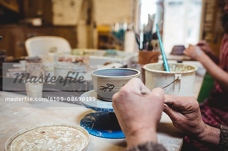 Cropped image of potters working at table in workshop