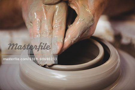 Cropped hands of craftsperson molding shape in pottery workshop