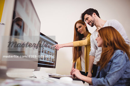 Businesswoman showing computer screen to coworkers in creative office