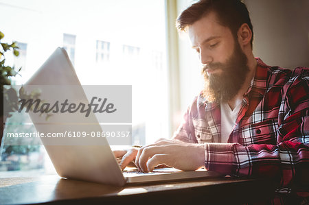 Young hipster using laptop at cafe