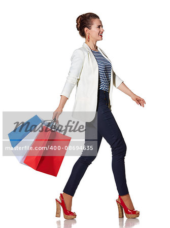 Shopping. The French way. Full length portrait of happy young woman with French flag colours shopping bags going to the side on white background