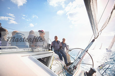 Retired friends on sailboat on sunny ocean
