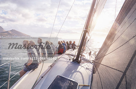 Retired friends sitting on sailboat on sunny ocean