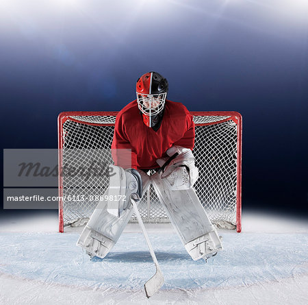 Portrait determined hockey goalie protecting goal net on ice