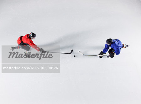 Overhead view hockey opponents going for the puck on ice