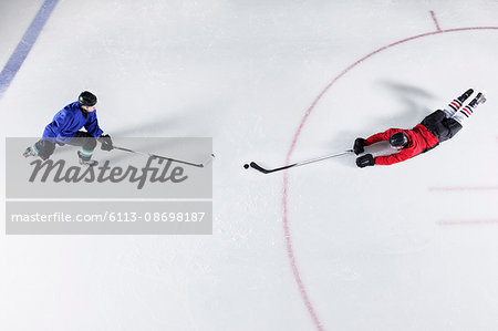 Overhead view hockey players diving for puck on ice