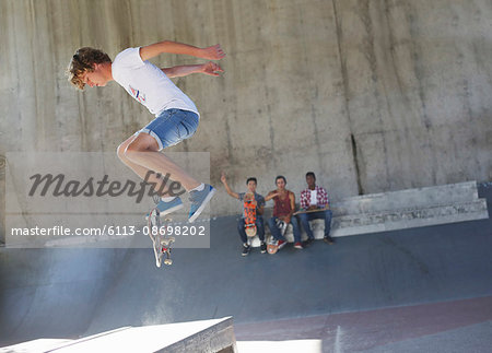 Teenage boy flipping skateboard at skate park