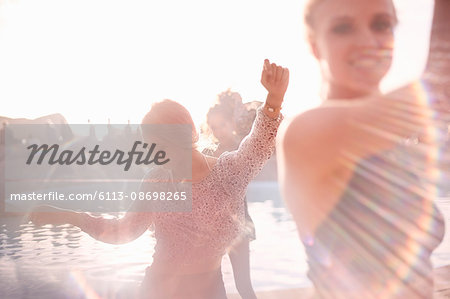 Young woman dancing at sunny poolside party