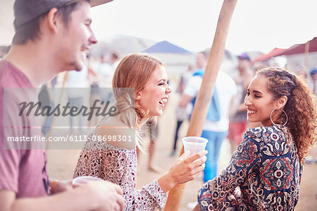 Young friends laughing and drinking at music festival