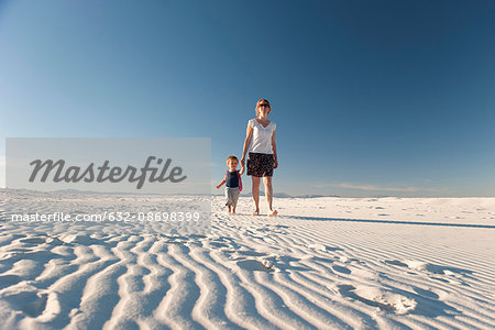 Mother and son walking on dune, White Sands National Monument, New Mexico, USA