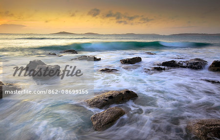 England, Isles of Scilly, St Marys. Waves and rocks at sunset.