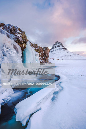 Snaefellsness peninsula, Western Iceland, Europe. Frozen Kirkjufellfoss waterfall in winter with Kirkjufell mountain in the backdrop.
