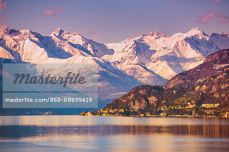 Varenna, Lecco, Lombardy, Italy. A winter sunset over Varenna with snow on the mountains on the backdrop.
