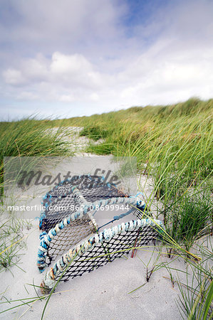 Scotland, Argyll and Bute, Isle of Tiree. Old lobster pot buried in sand dunes.