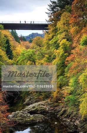Scotland, Pitlochry. People on the bridge over the River Garry in autumn, near the Pass of Killiecrankie.