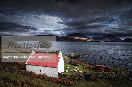 Scotland, Wester Ross. A brightly coloured cottage beside Loch Shieldaig on a gloomy day.