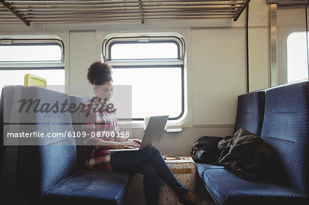 Woman using laptop while sitting in train