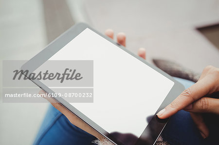 Cropped image of woman using tablet computer while sitting outdoors