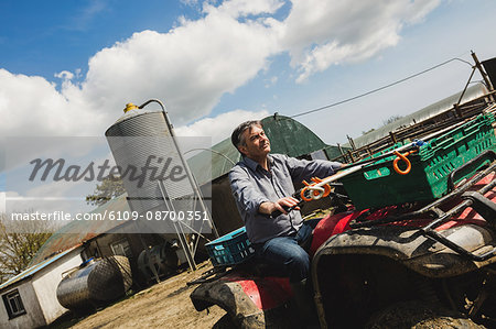 Tilt image of farmer riding quadbike at field against sky