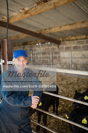 Portrait of happy farm worker standing by fence at shed