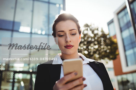 Young businesswoman using mobile phone against building