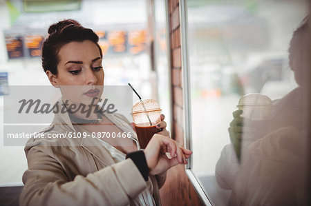 Young woman checking time by board at railroad station