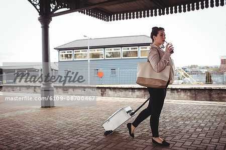 Full length of young woman carrying suitcase at railroad station platform