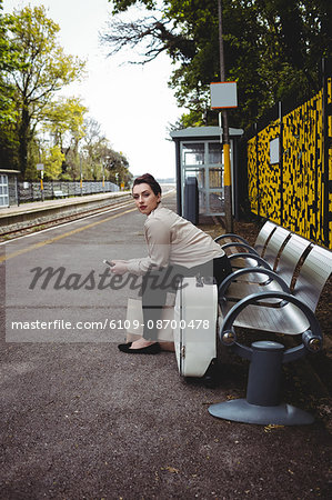 Beautiful woman sitting on bench at railroad station platform
