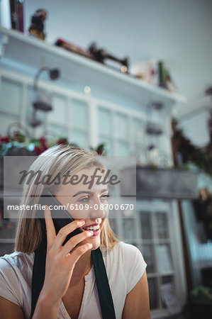 Female florist talking on mobile phone in the flower shop
