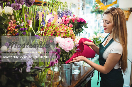 Female florist pouring water in flower vase at her flower shop