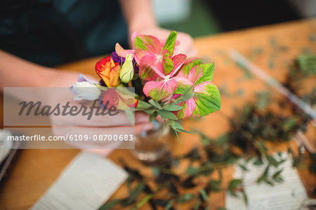 Close-up of female florist arranging flowers in a bottle at her flower shop